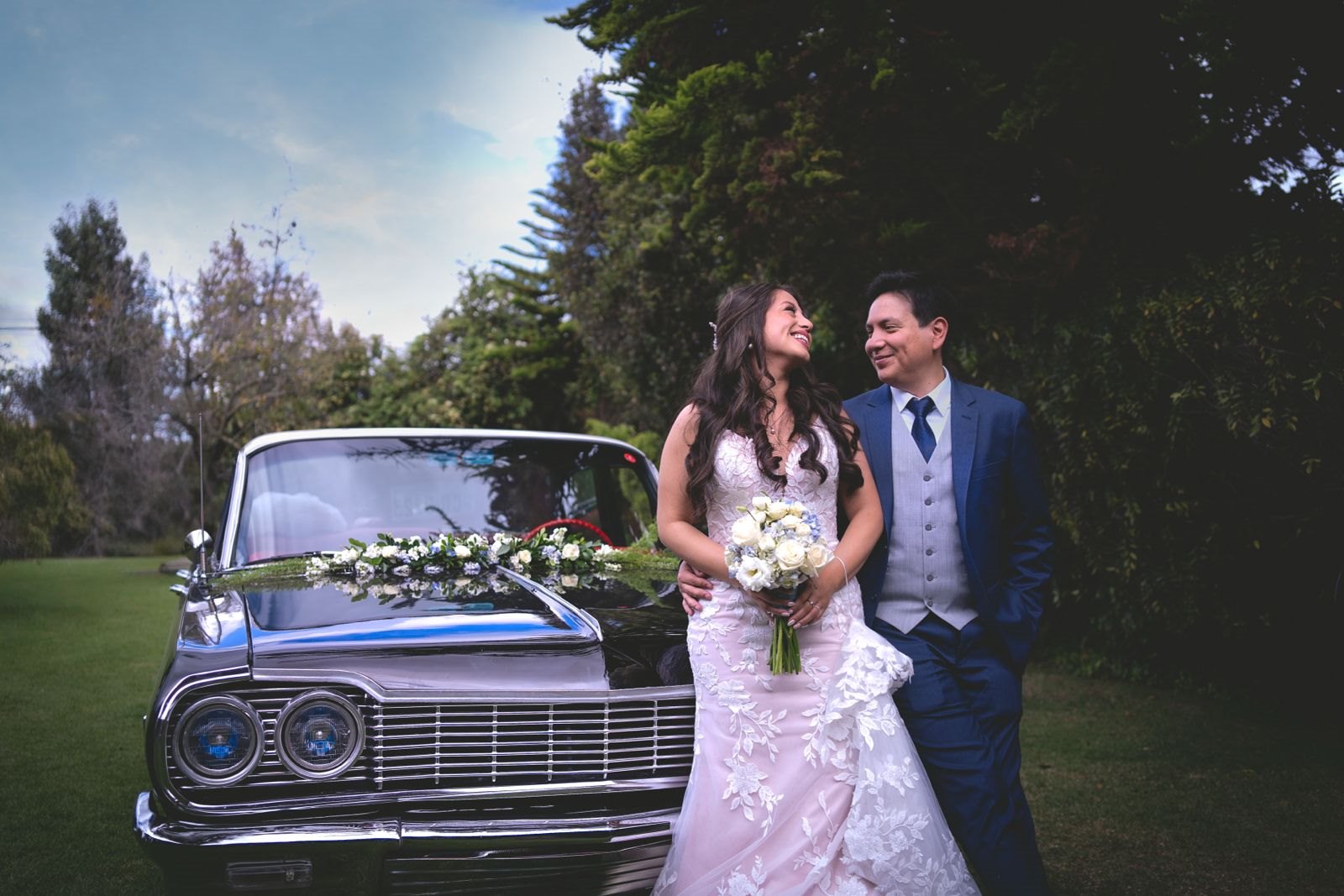 Novios junto a un automóvil clásico decorado con flores